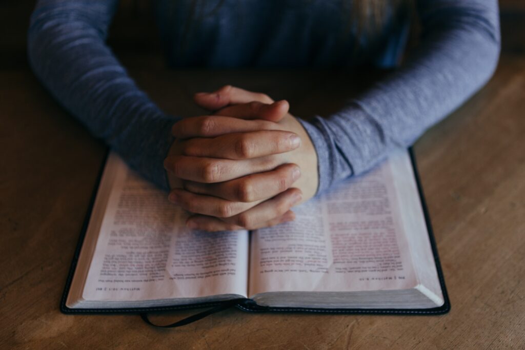 man praying using prayer structure over Bible